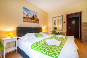a bedroom with a large bed with a green blanket at Hotel Bobbio in Budapest