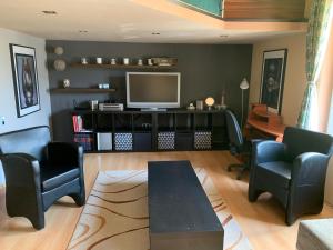 a living room with two chairs and a television at Pláza Home in Siófok