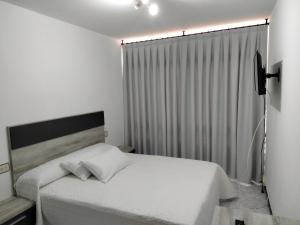 1 dormitorio con cama blanca y ventana en A Casa de Lolita en Muros