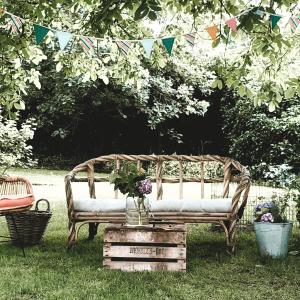 a wooden bench sitting in the grass with flowers on it at Bed & Breakfast Neeltje Soet in Mierlo +14 photos