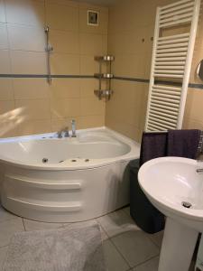 a bathroom with a bath tub and a sink at Pláza Home in Siófok +9 photos