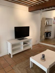 una sala de estar con TV en un armario blanco en Au 10, en LʼIsle-sur-la-Sorgue