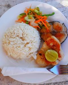 um prato branco com arroz e legumes e uma refeição em Fisherman Lodge em Paje