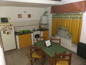 Una cocina con mesa y sillas y un refrigerador. en Apartamento El Calvario 3, en Tandil