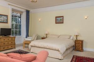 a bedroom with a bed and a tv and a couch at Lammas Park House in Dawlish