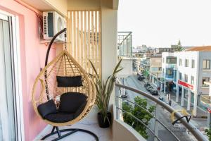 een rotan stoel op een balkon met uitzicht op de stad bij City Vibes apartment Preveza in Preveza