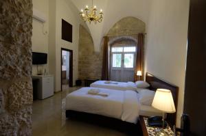 a bedroom with a large bed and a chandelier at St. George’s Cathedral Pilgrim Guesthouse – Jerusalem in Jerusalem