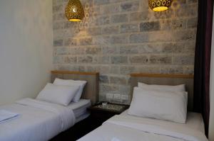two beds in a room with a brick wall at St. George’s Cathedral Pilgrim Guesthouse – Jerusalem in Jerusalem