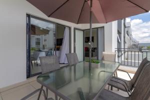 a glass table with chairs and an umbrella on a balcony at Villa Valentino Greenstone Ridge WiFiNetflix in Edendale