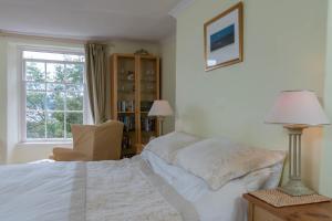 a bedroom with a bed and a chair and a window at Lammas Park House in Dawlish