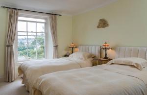 2 camas en un dormitorio con ventana en Lammas Park House, en Dawlish