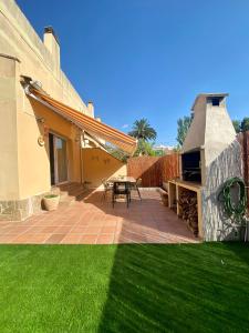 a patio with a grill and green grass at CAN LOLA Estupenda casa de 4 habitaciones con jardín a 150 metros de la playa in Torredembarra