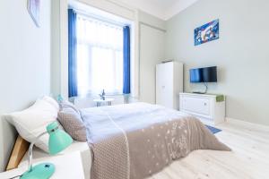 a white bedroom with a bed and a window at Central Studio Budapest in Budapest