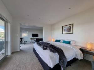 a bedroom with a bed and a desk and a television at Fabulous Castor Bay 1 Bedroom With Views and SkyTV in Auckland