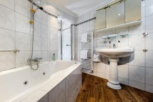ein Badezimmer mit einer Badewanne, einem Waschbecken und einer Badewanne in der Unterkunft Hotel Reethüüs in Kampen