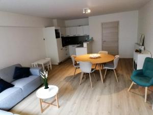 a living room with a couch and a table and chairs at Hakuuna Matata Appartement Koksijde met staanplaats in Koksijde