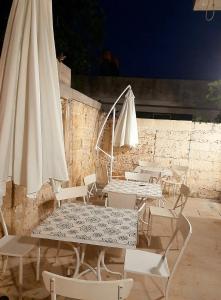 eine Gruppe von Tischen und Stühlen mit einem weißen Schirm in der Unterkunft Casa di Carmine 2 in Galatina