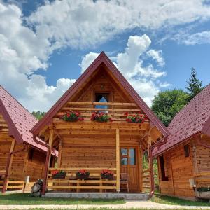 a log cabin with flowers in the window at Drveni raj Uvac in Sjenica