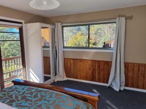 a bedroom with a bed and two windows at Cradle Alpine Retreat in Moina