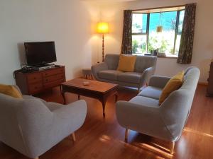 - un salon avec deux canapés et une télévision dans l'établissement Wakari Holiday Home, à Dunedin