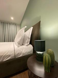 1 dormitorio con cama con almohadas blancas y mesa en Santuário Fátima - Host 2AP5, en Fátima