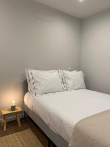 a bedroom with a white bed with a candle on a table at Santuário Fátima - Host 2AP5 in Fátima