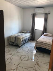 a room with two beds and a tiled floor at Lindo Apartamento ! in Manaus