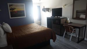 a hotel room with a bed and a desk with a television at La Villita Inn in San Antonio +37 photos