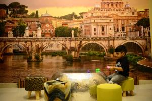 a young boy sitting on a chair in front of a bridge at Kaleidoscope in Ajman 