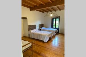 2 Betten in einem Zimmer mit Holzböden in der Unterkunft Preciosa casona con hórreo in Ribadesella