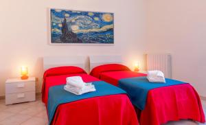 2 rote Betten in einem Zimmer mit Wandgemälde in der Unterkunft B&B Torre Lauro in Sciacca