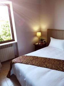 Hotel Corte Dal Castello في كولا دي لاتيزي: غرفة نوم بسرير ابيض ونافذة