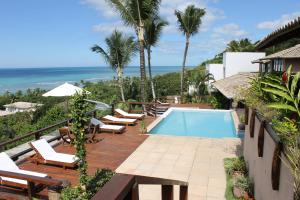 a resort with a pool and chairs and the ocean at Baixu Village in Arraial d'Ajuda