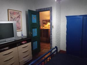 a living room with a tv and a blue door at Criatividade na Serra in Petrópolis