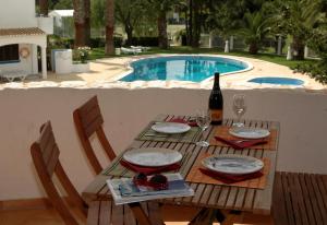 a table with a bottle of wine next to a pool at Turiquintas in Armação de Pêra