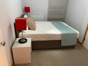 1 dormitorio con cama y mesita de noche con lámpara en GREENWICH CENTRE NKY APARTMENT en Londres
