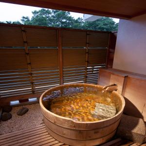 d'une grande baignoire en bois installée au-dessus d'un balcon. dans l'établissement Zazan minakami, à Minakami