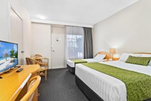 
a bedroom with a bed and a desk at Park Motor Inn in Toowoomba
