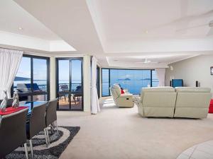 a living room with white furniture and a view of the ocean at Seaside Splendour 1 beautiful unit on the waterfront in Salamander Bay