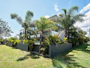 a building with palm trees in front of it at Shoal Bay Beach Apartments 18 fantastic air conditioned unit with a pool and lift in Nelson Bay