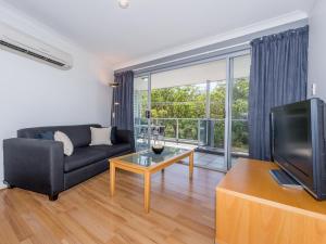 a living room with a couch and a tv at Shoal Bay Beach Apartments 18 fantastic air conditioned unit with a pool and lift in Nelson Bay