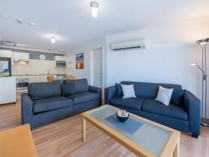 a living room with two blue couches and a table at Shoal Bay Beach Apartments 18 fantastic air conditioned unit with a pool and lift in Nelson Bay