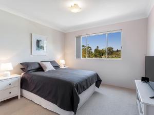 a white bedroom with a bed and a window at Cottage Court 4 Shoal Bay and Little Beach at your fingertips in Nelson Bay