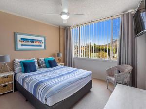 una camera da letto con un letto e una grande finestra di Magnus Gardens 4 beautiful air conditioned unit with filtered water views and Wi-Fi a Nelson Bay