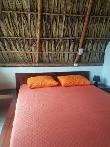 a bed with two orange pillows in a room at Mi Casa en la Playa in Escuintla