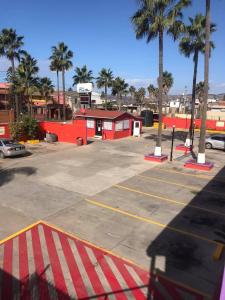een parkeerplaats met palmbomen en een rood gebouw bij COSTA MAR in Ensenada