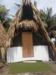 une maison avec un toit de chaume et une porte dans l'établissement Mi Casa en la Playa, à Escuintla