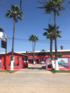 een rood gebouw met palmbomen ervoor bij COSTA MAR in Ensenada