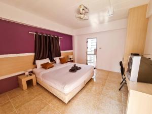 1 dormitorio con 1 cama grande y pared morada en Sleep CNX en Chiang Mai