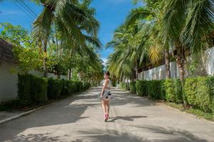 a woman walking down a road with palm trees at Dhevan Dara Resort & Spa Hua Hin - Pool Villa in Hua Hin